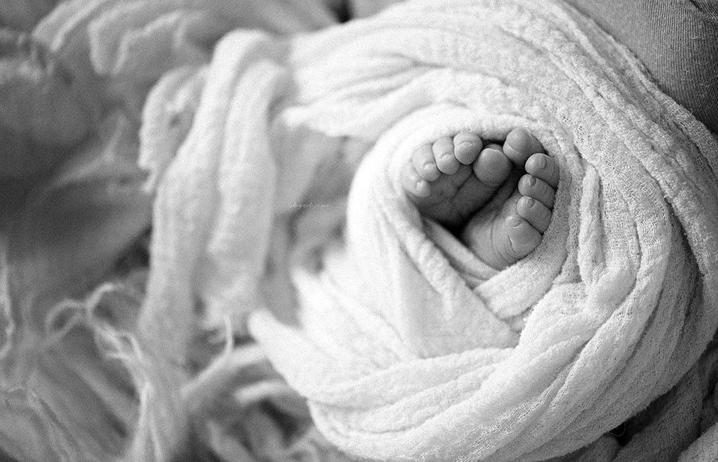 black and white photo of newborns toes wrapped in swaddle
