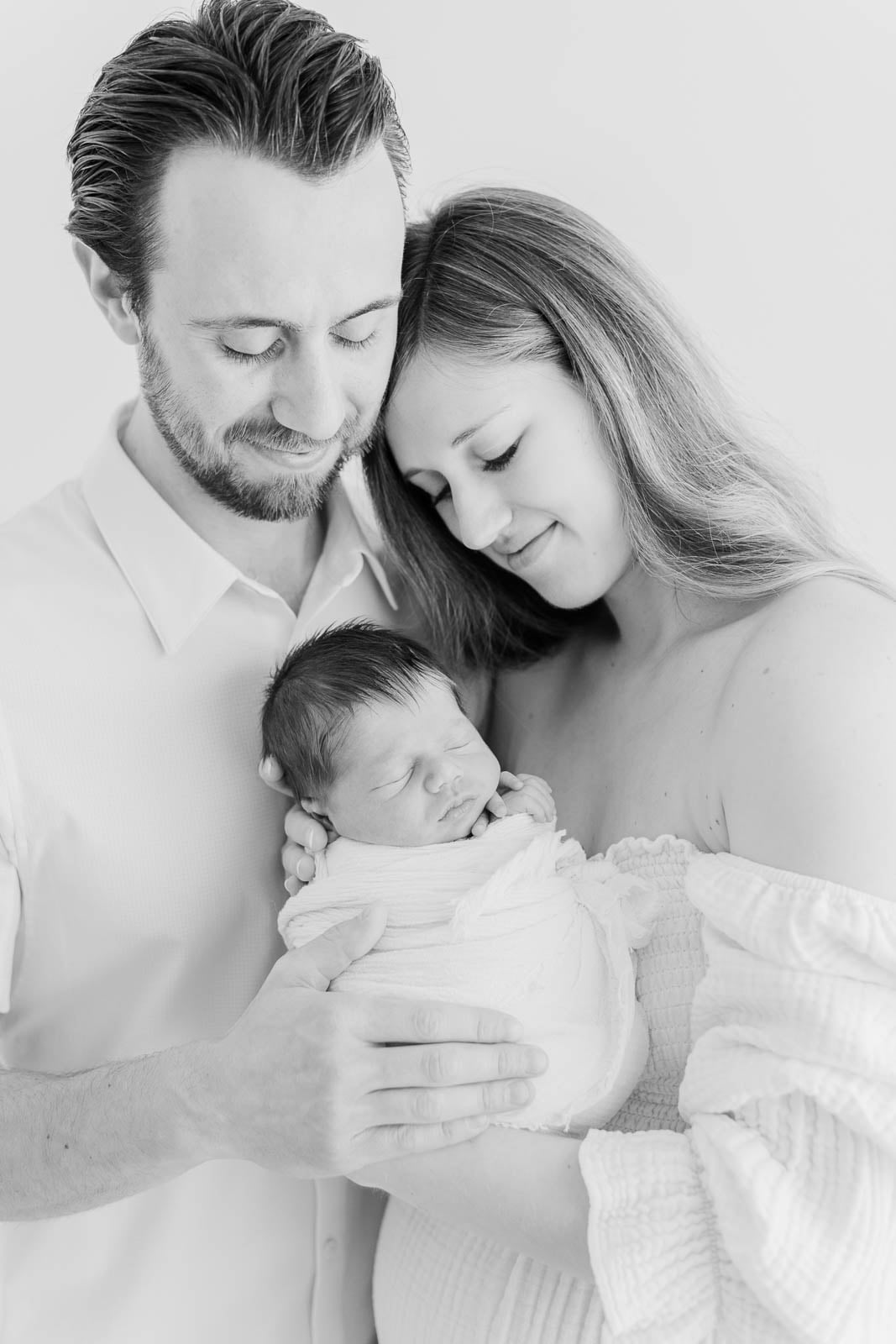 Intimate black and white portrait by a Chicago maternity photographer featuring a loving couple cradling their newborn baby.
